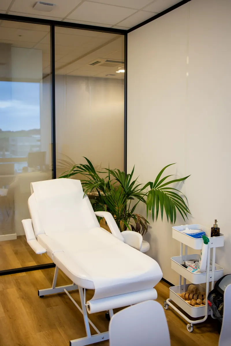 Salle de soin calme avec table de soin blanche et palmier au cabinet Euphoria Laser